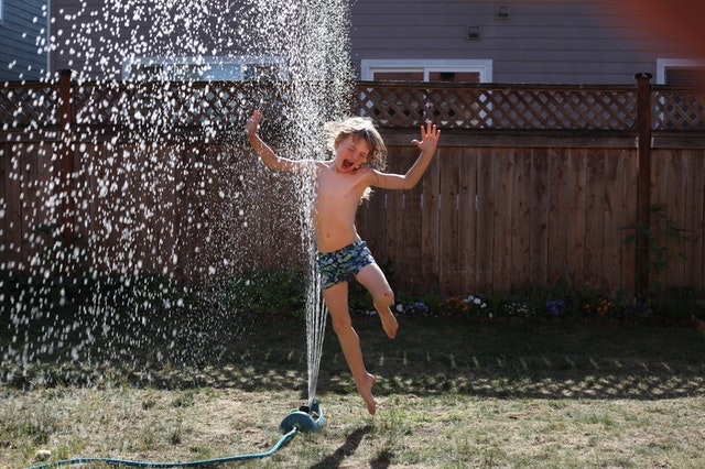 Kid jumping through sprinkler